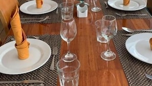 Uma longa mesa de jantar com cadeiras, pratos e copos de vinho dispostos para uma refeição.