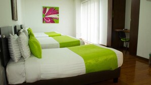 Quarto de hotel com duas camas, uma escrivaninha e uma cadeira.