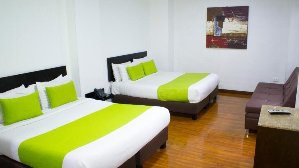 Ein Hotelzimmer mit zwei Betten, einem Schreibtisch und einem Bild an der Wand.