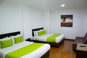 Une chambre d’hôtel avec deux lits, un canapé, un tableau au mur et une télécommande sur la table.