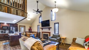A spacious living area with a high ceiling, a fireplace, a television, and a dining area. - Covered Porch & Grill: 1-Acre Property in Bristow! (Bristow)