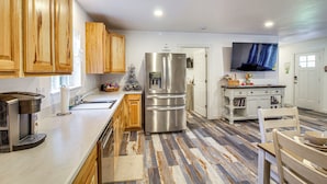A modern kitchen with wooden cabinets, stainless steel appliances, and a patterned floor. - Near Ocean: 'Home Away From Home' in Gold Beach (Gold Beach)