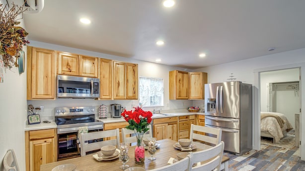 A modern kitchen with wooden cabinets, stainless steel appliances, and a dining table set for four. - Near Ocean: 'Home Away From Home' in Gold Beach (Gold Beach)