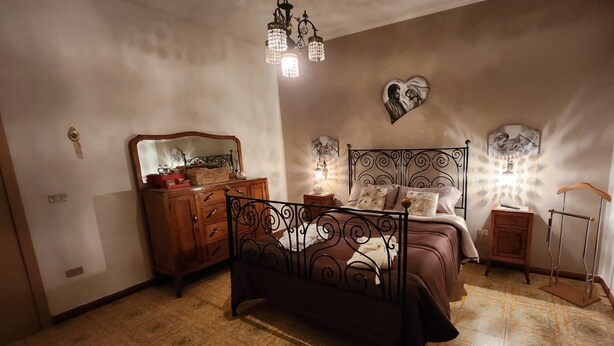 A bedroom with a bed, dresser, mirror, and decorative wall art. - Cozy apartment a few meters from the Baiano highway exit. (Sirignano)