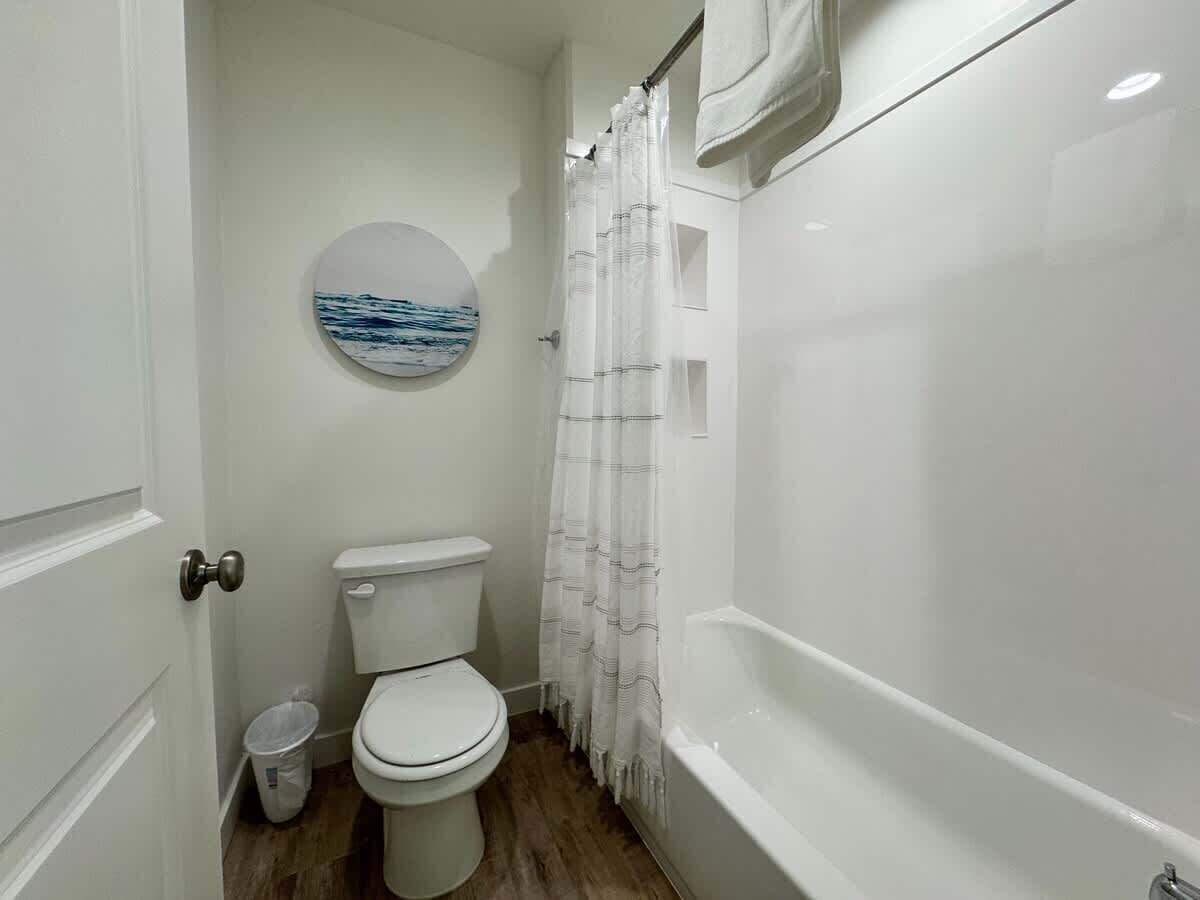 A small, clean bathroom with a toilet, a bathtub, and a shower curtain.