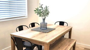 A wooden dining table with a bench, black chairs, and a vase with greenery. - Close to Marina & Market · 3BR House · Sleeps 10 (Garden City)