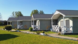 A row of single-story, light-colored mobile homes with grey roofs, white railings, and small front yards. - Holiday Homes Close to the Seaside Beach (Mielno)