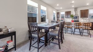 A modern kitchen with dark wooden cabinets, a central island, and a dining area with dark wooden chairs.
