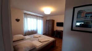Una habitación de hotel con cama, escritorio, televisor y un cuadro en la pared.