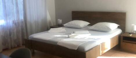 A neatly made bed with white linens, a wooden headboard, and a bedside table with a lamp.
