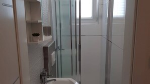 Un baño moderno con cabina de ducha de vidrio, un lavabo blanco y un inodoro.