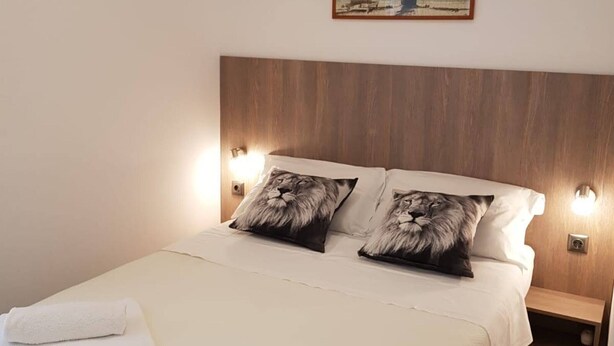 Una cama con dos almohadas con diseño de león, un cabecero de madera y un cuadro de una escena de playa sobre la cama.