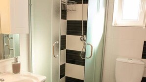 Une salle de bain avec une douche à parois de verre, un lavabo blanc et des toilettes.