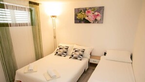 Une chambre avec deux lits, une table de chevet, une lampe et un tableau représentant des fleurs accroché au mur.
