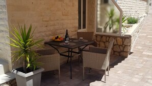 Une terrasse extérieure avec une table et des chaises, une plante en pot et un mur de pierres.