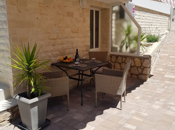 Eine Terrasse im Freien mit Tisch, Stühlen, einem Blumentopf und einer Steinmauer.