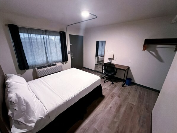 Una habitación pequeña con cama, escritorio y silla.