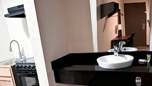 A modern kitchen with a black countertop, white sink, and stainless steel appliances. - Studio City Suites, A Travelodge By Wyndham (Texarkana)