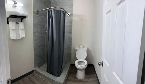 A bathroom with a shower, toilet, and towel rack.