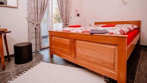 A bedroom with a wooden bed, a small table, a chair, and a window with curtains.