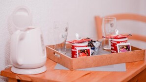 A tray with two Nescafé coffee containers, two glasses, and a white coffee maker on a wooden table.