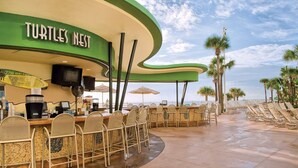 Un restaurant a la vora de la platja anomenat 'Turtle's Nest', amb seients a l'aire lliure i palmeres al fons.