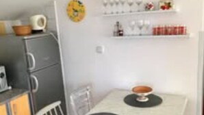 Une cuisine compacte comprenant une petite table à manger, un réfrigérateur et un four à micro-ondes.