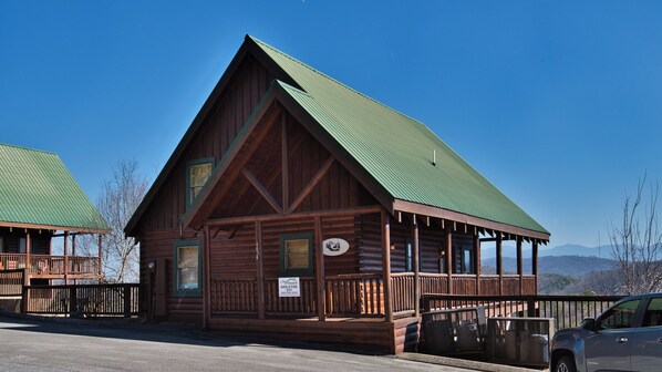 A log cabin-style building with a green roof, a porch with railings, and a sign indicating it is a Breathe Inn. - Resort Setting cozy cabin with community outdoor pool and spectacular views. (Pigeon Forge)