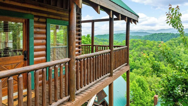 Une cabane en bois dotée d’un balcon donnant sur un paysage boisé.