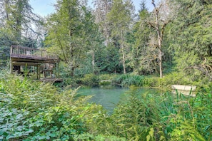 A wooden deck with a railing overlooking a pond surrounded by dense greenery. - 4 Mi to Sandy, Oregon: Studio w/ Mtn View (Sandy)