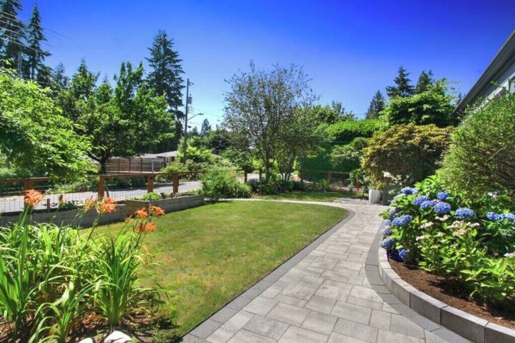 A landscaped garden with a curved pathway, various shrubs, and flowering plants.