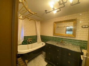 Une salle de bain avec une baignoire blanche, un lavabo doté d’un plan de toilette en marbre et un meuble-vasque avec des placards sombres.