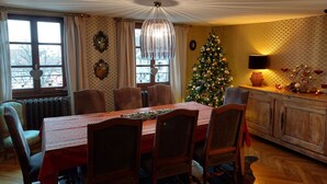 Un comedor con una mesa y sillas de madera, un árbol de Navidad y una araña.