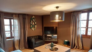 Una sala de estar con un sofá, una mesa de centro, un televisor y un elemento decorativo en la pared.