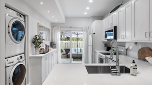 A modern kitchen with built-in appliances, a central island, and a view to an outdoor patio. - Hide Tide Hideaway at Carlin Park (Jupiter)