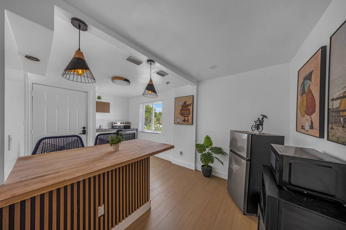 A modern kitchen with a wooden island, black appliances, and pendant lighting.