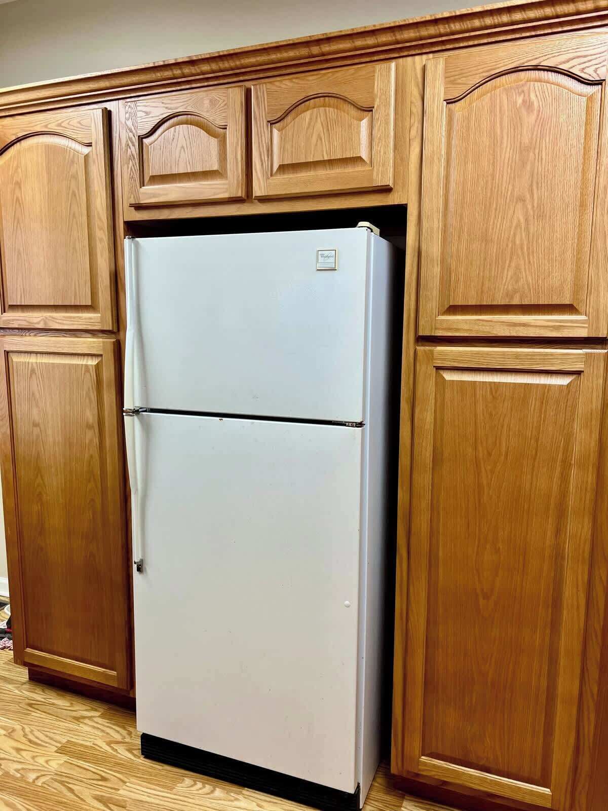 Una cocina con armarios de madera y un refrigerador blanco.