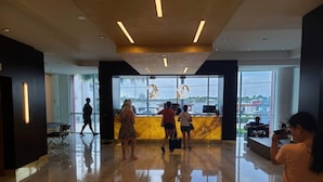 A modern lobby with a reception desk, large windows, and a polished floor. - Hollywood Beachfront Apartment at COSTA (Hollywood)