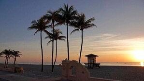 A beach scene with palm trees and a lifeguard tower at sunset. - Hollywood Beachfront Apartment at COSTA (Hollywood)