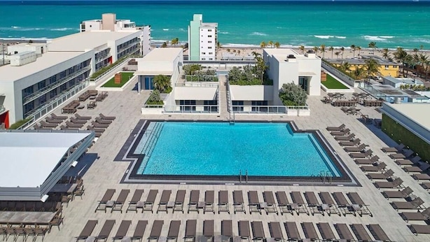 A rooftop pool with sun loungers, a clear view of the ocean, and a modern building with a flat roof. - Hollywood Beachfront Apartment at COSTA (Hollywood)