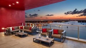 A spacious balcony with a city view at sunset, featuring a sofa set and a coffee table. - Hollywood Beachfront Apartment at COSTA (Hollywood)