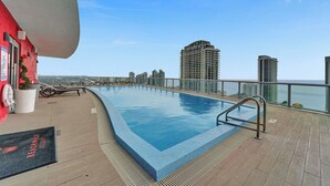 A rooftop pool with a city view, lounge chairs, and a sign for Beachwalk Resort.