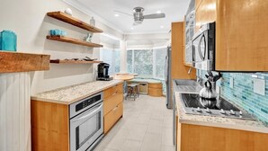 A modern kitchen with wooden cabinets, a built-in oven, a stovetop, and a ceiling fan.