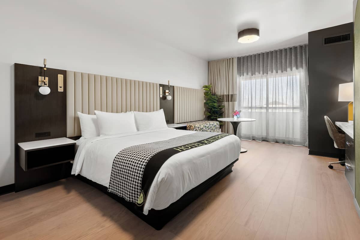 A hotel room with a large bed, bedside tables, a desk, and a chair.