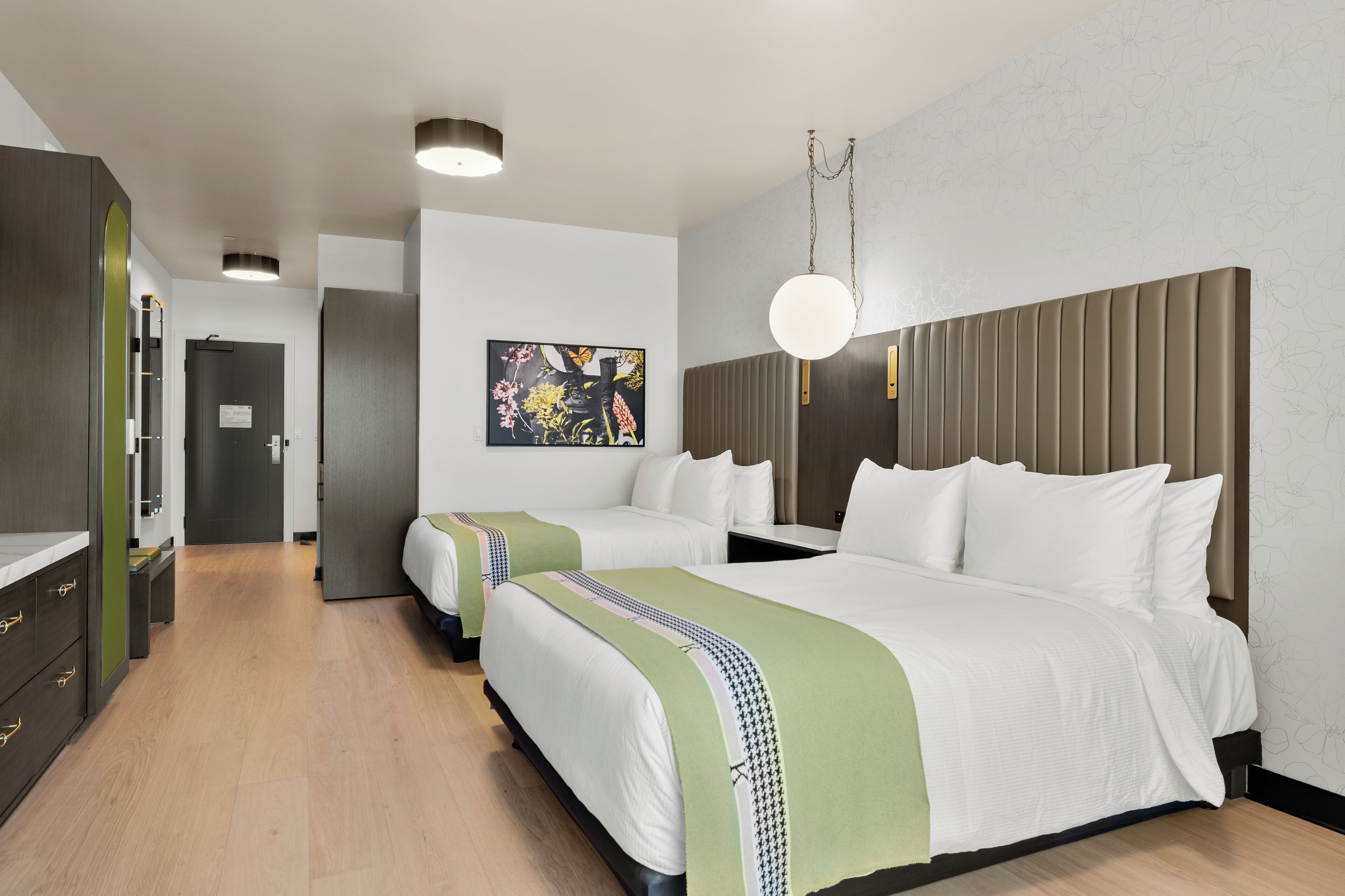 Habitación de hotel con dos camas, un armario, un cuadro en la pared y una lámpara en el techo.