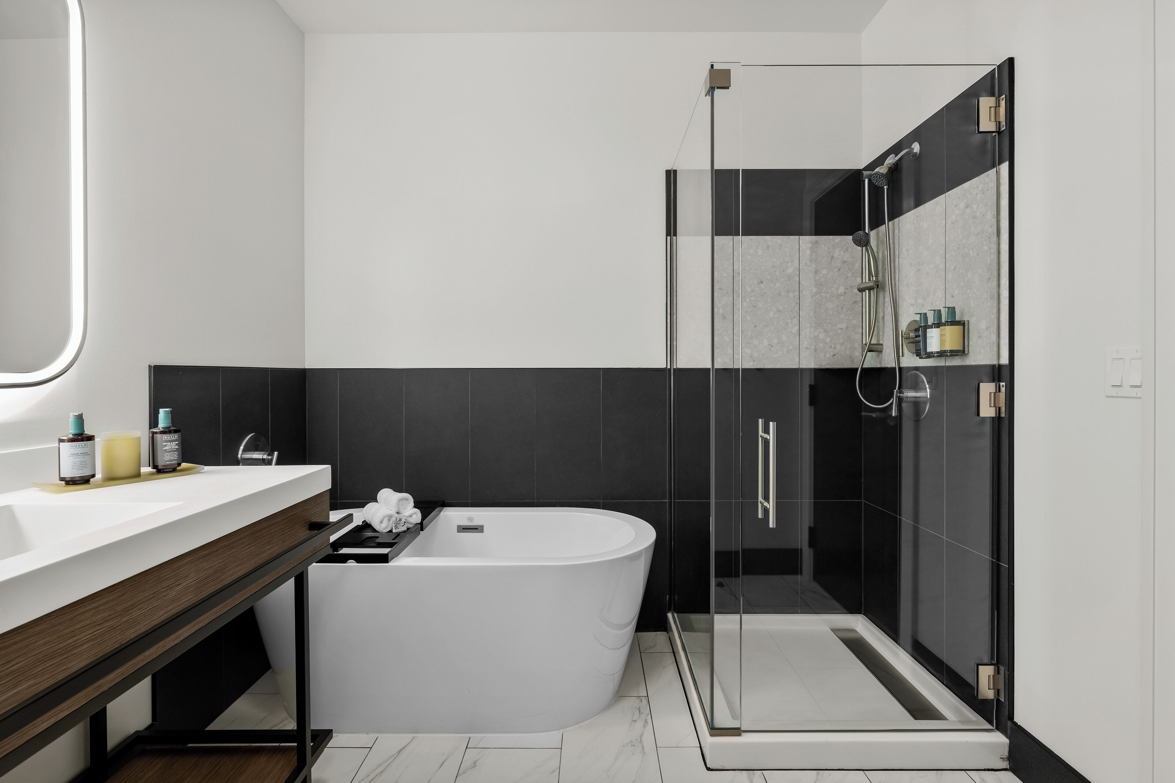 A modern bathroom with a freestanding bathtub, a glass-enclosed shower, and a vanity with a mirror.