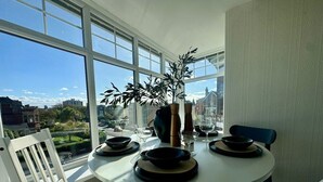 A dining area with a round table, white chairs, and a potted plant.