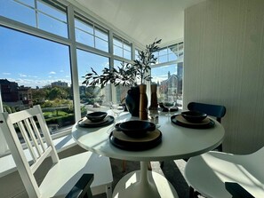 Un comedor con una mesa redonda, sillas blancas y una planta en maceta.