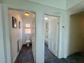 Un pasillo que conduce a un baño con inodoro, ducha y bañera.