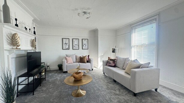 A living room with a fireplace, two sofas, a coffee table, and a television.